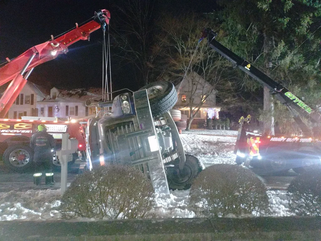 Citywide wreckers uprighting an overturned truck at night in the snow in Putnam Valley, NY